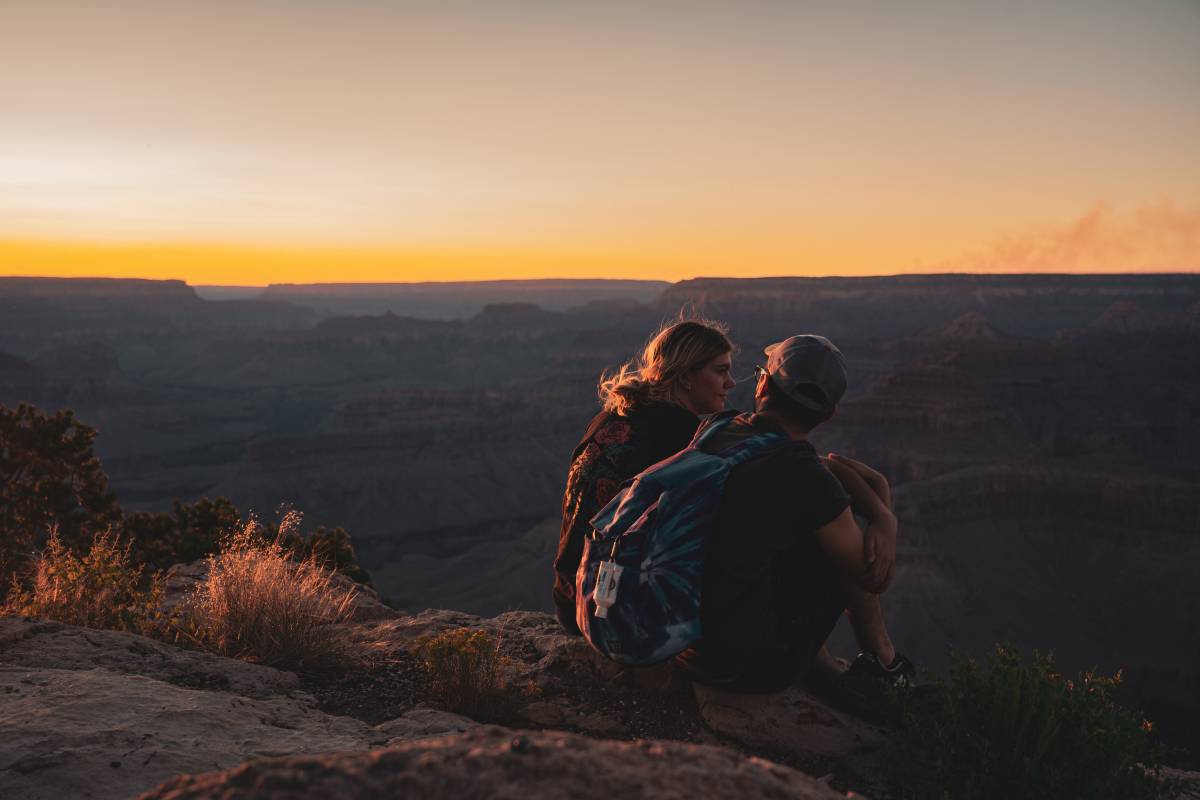 Mann und Frau sitzen bei Sonnenuntergang auf einem Berg