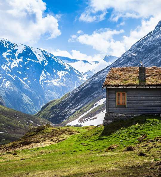 Berghütte auf einer Wiese im Sommer zwischen den Alpen