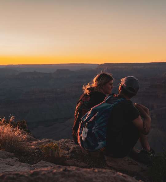 Pärchen sitzt auf Berg bei Sonnenuntergang