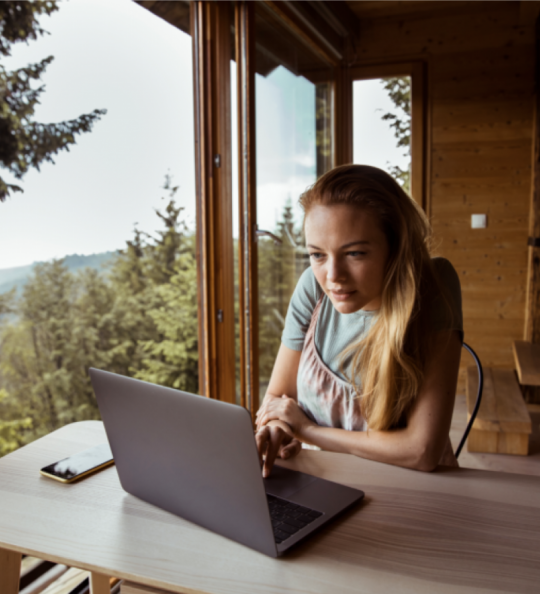 Frau sitzt am Laptop in einer Berghütte